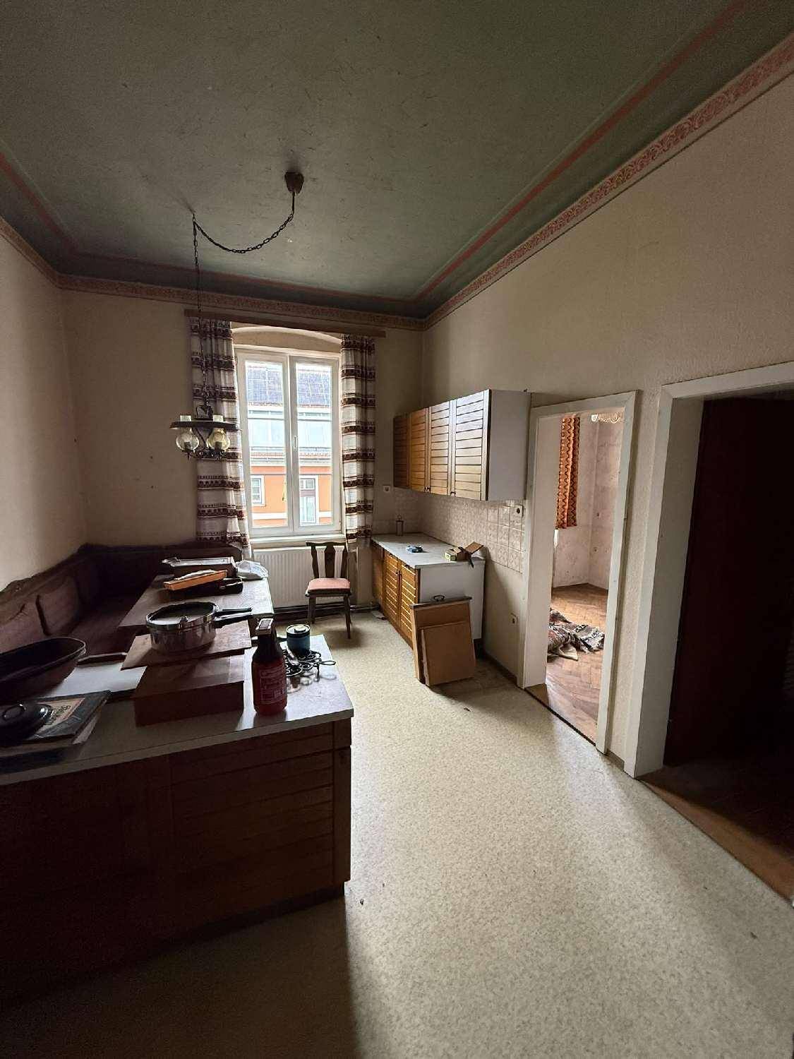 Kleine Küche mit älteren Einbauschränken, einem Fenster und einfacher Ausstattung.