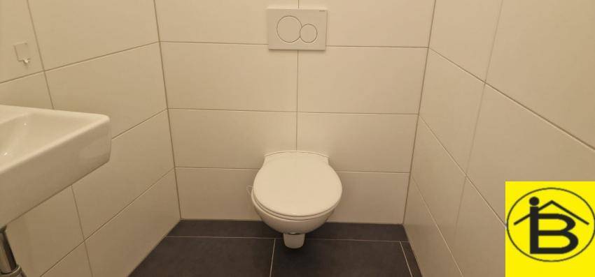 Separates Gäste-WC mit wandhängender Toilette und weißen Fliesen.