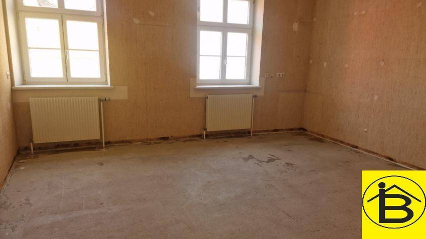 Raum mit zwei Fenstern und Heizkörpern, die Wände sind für eine Renovierung vorbereitet.
