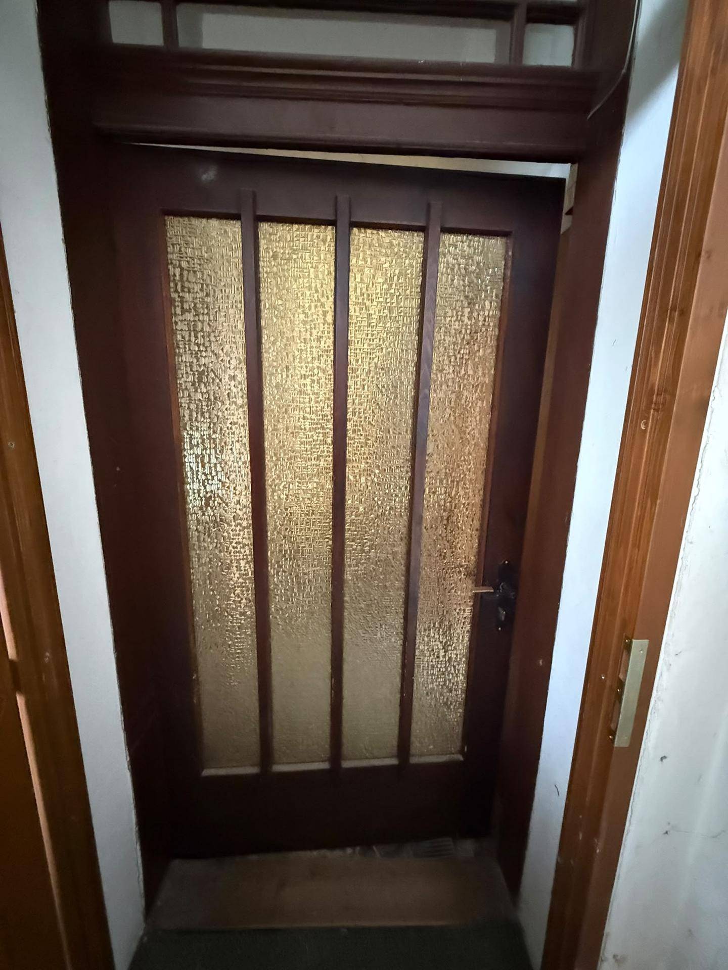Detailaufnahme einer alten Holztür mit strukturierten Glaspaneelen.