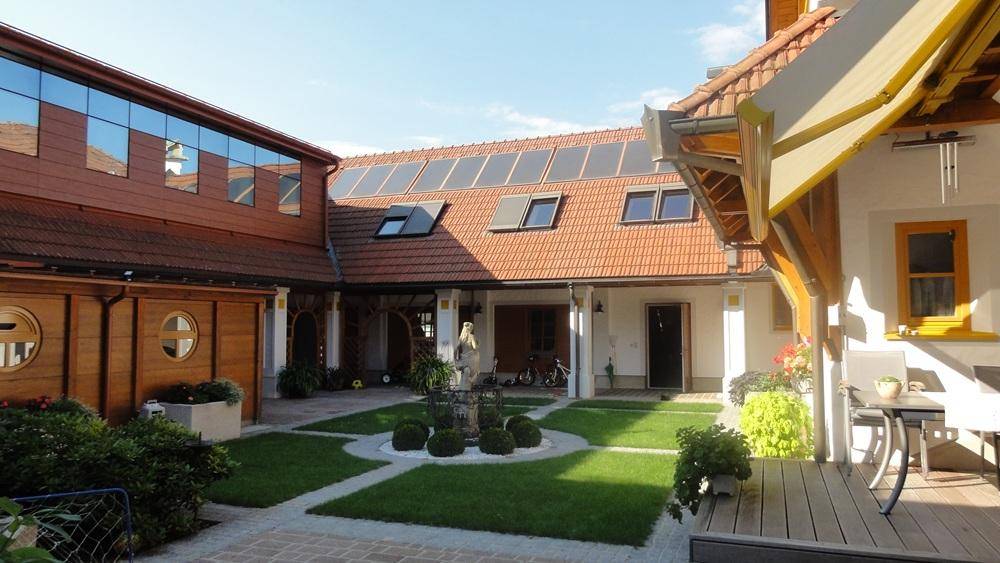 Innenhof mit Solaranlage auf dem Dach, Springbrunnen und gemütlichem Sitzbereich im Freien.