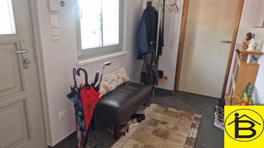 Eingangsbereich mit Garderobe, Sitzbank und Fliesenboden.