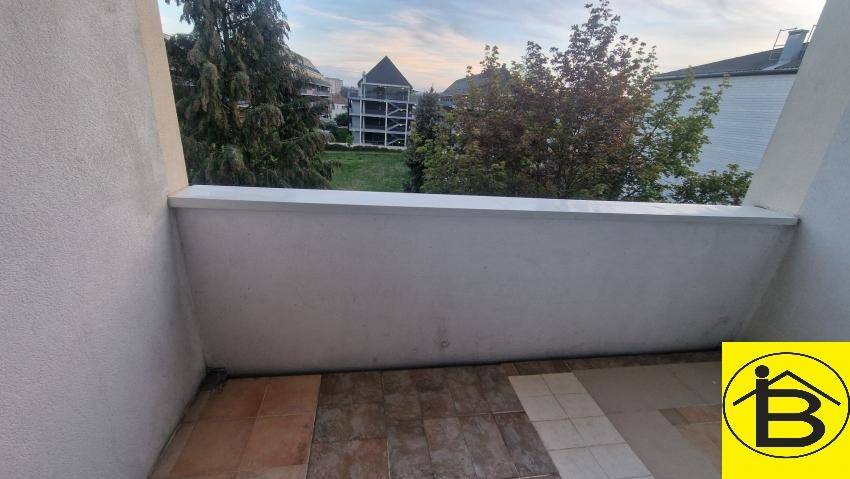 Kleiner Balkon mit Fliesenboden und Blick ins Grüne.