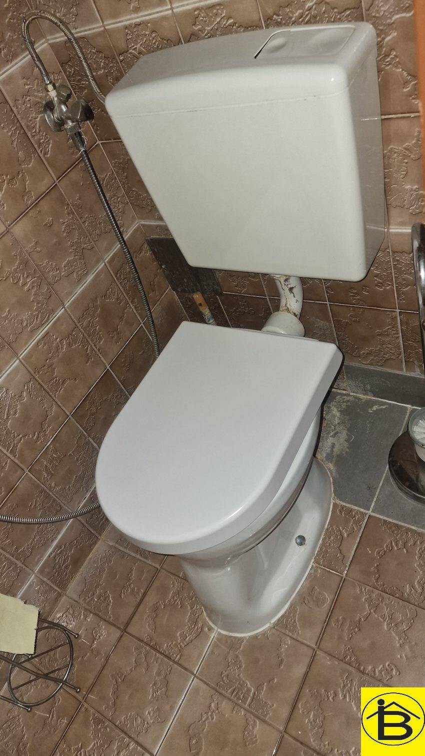 Separate Toilette mit Fliesenboden und Wand-WC.