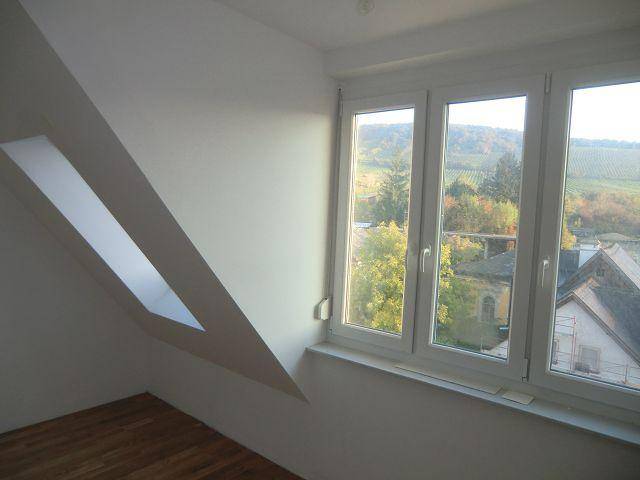 Zimmer mit Holzboden und weitem Blick auf die umliegende Landschaft und Weinberge.