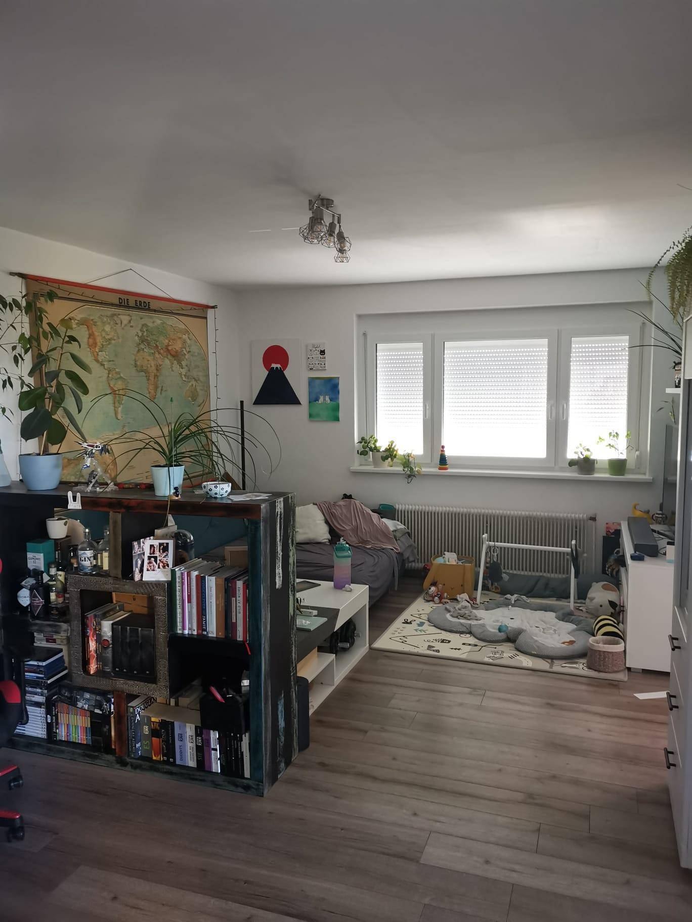 Gemütlicher Wohnbereich mit Holzboden, großem Fenster und Spielbereich.