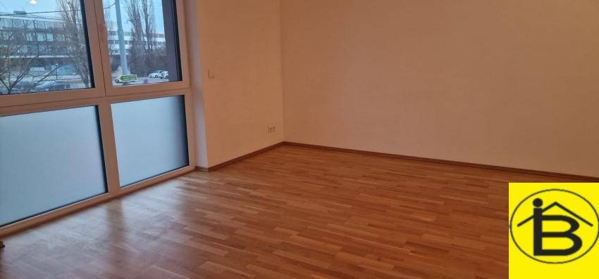 Geräumiger Raum mit Holzboden und großem Fenster, bietet Blick auf die Straße.