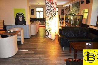 Offener Loungebereich mit verschiedenen Sitzgelegenheiten, Holzboden und kreativer Wandgestaltung.