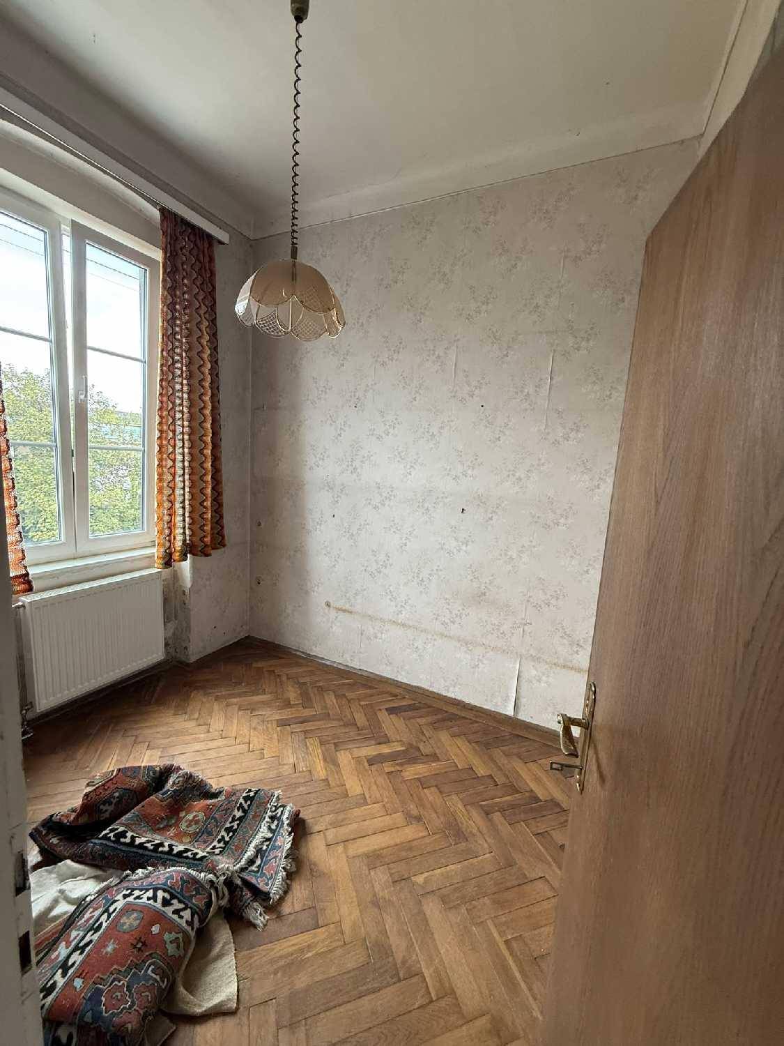 Leeres Zimmer mit Fischgrätparkettboden und einem Fenster, das viel Licht hereinlässt.