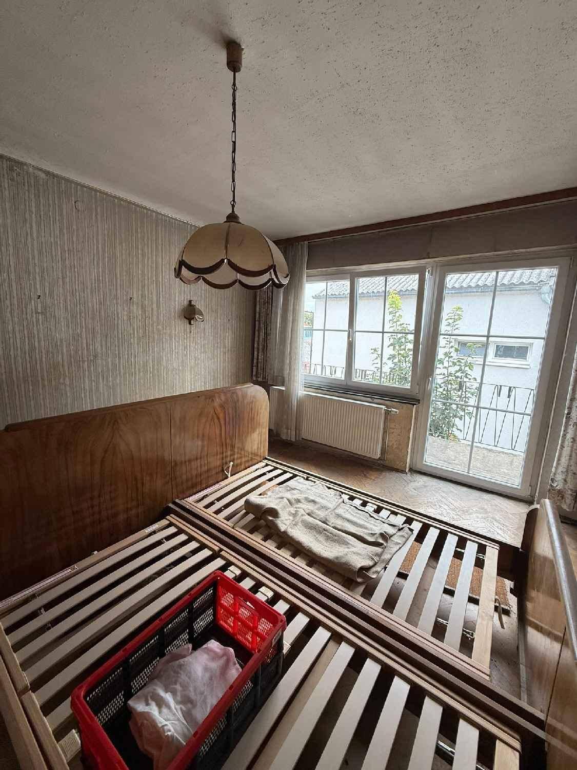 Schlafzimmer mit Bettrahmen und großen Fenstern, die zu einem französischen Balkon führen.