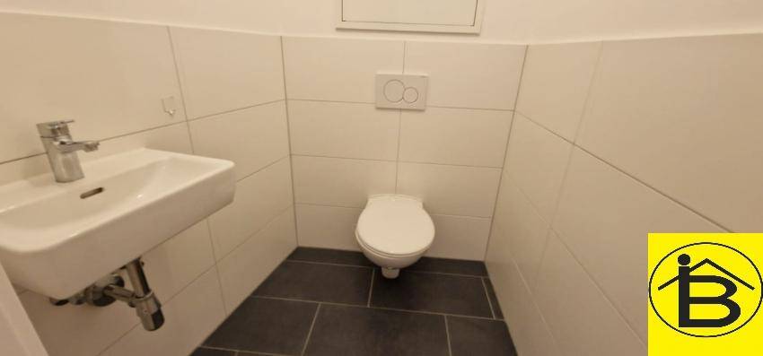 Separates Gäste-WC mit wandhängender Toilette und kleinem Waschbecken.