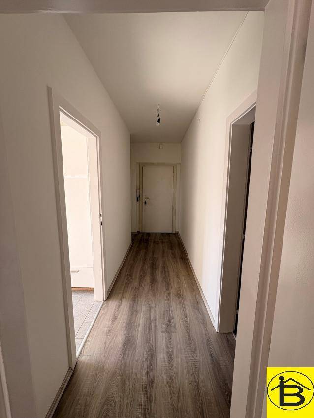 Geräumiger Flur mit Laminatboden und weißen Wänden, der einen klaren Zugang zu den Räumen bietet.