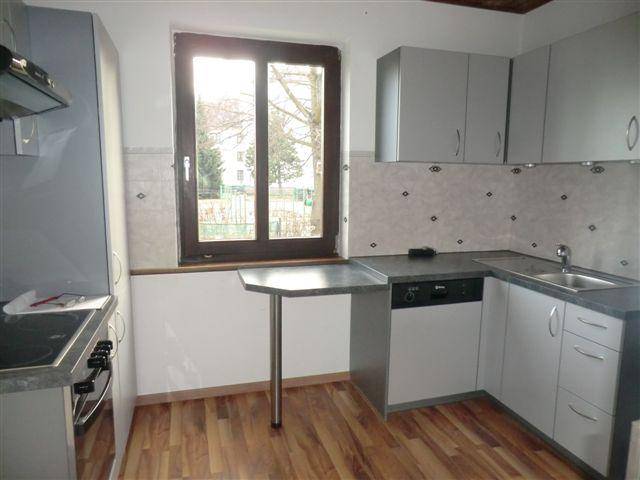 Helle Küche mit Spüle, Geschirrspüler und einem kleinen Tisch am Fenster, ideal für schnelle Mahlzeiten.
