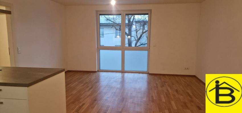 Heller Wohnbereich mit großem Fenster und Holzboden, bietet viel Tageslicht.