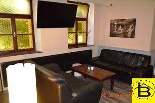 Entspannter Loungebereich mit schwarzen Ledersofas, Couchtisch und dekorativen Fenstern.