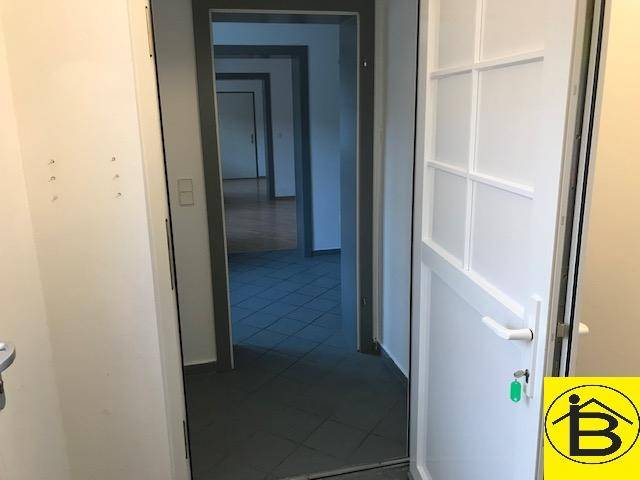 Eingangsbereich mit Fliesenboden, der zu weiteren Räumen mit Holzparkett führt.