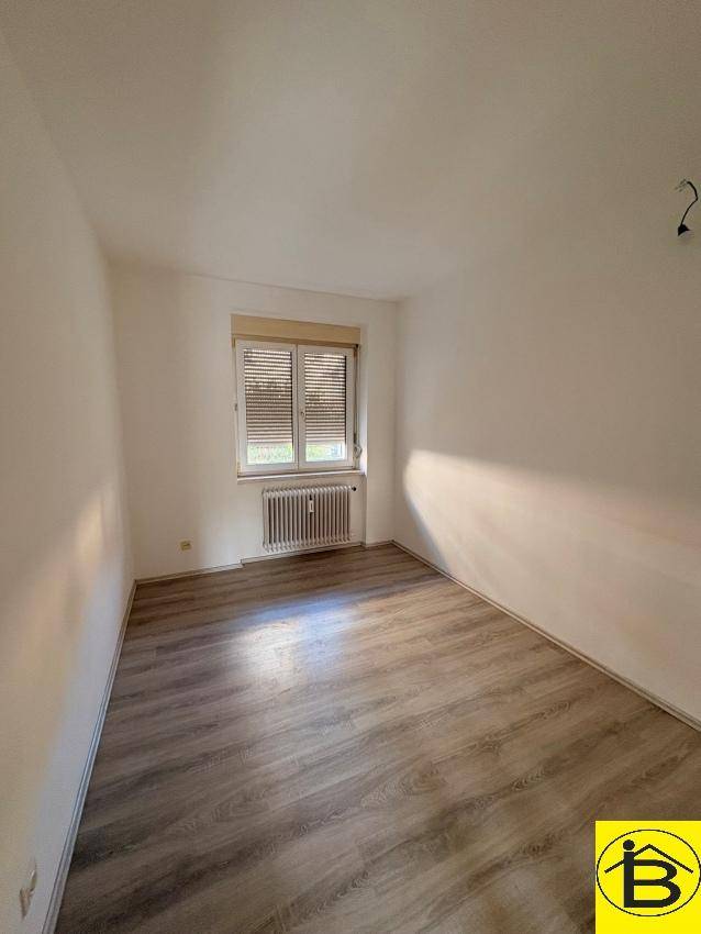 Gemütliches Schlafzimmer mit Laminatboden und Fenster mit Jalousien, ideal für Ruhe und Entspannung.