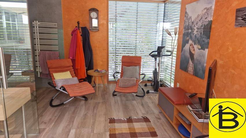 Entspannungsbereich mit Fitnessgerät, Liegestühlen und großen Fenstern.