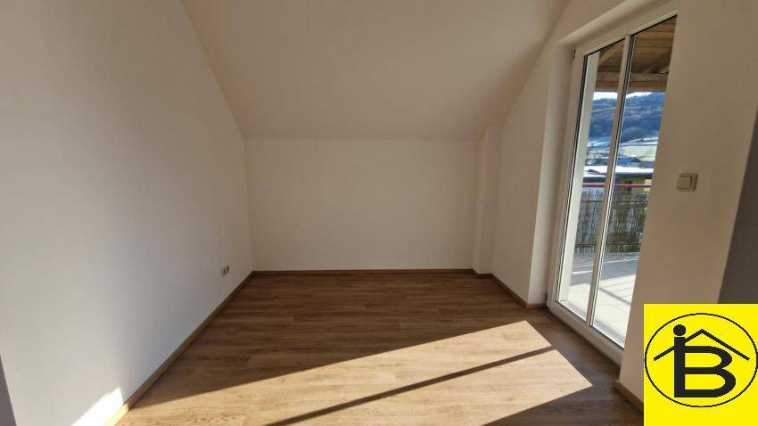 Lichtdurchflutetes Zimmer mit Holzboden und Zugang zu einem Balkon, ideal für ein Schlafzimmer.