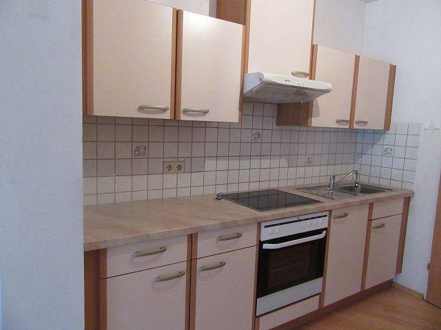 Funktionale Küche mit hellen Schränken, Fliesenrückwand und integriertem Kochfeld und Backofen.