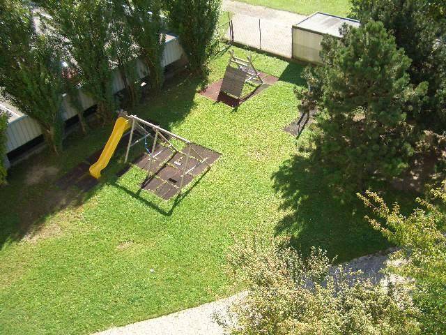 Grüner Spielplatz mit Rutsche und Schaukeln, ideal für Kinder im Freien.