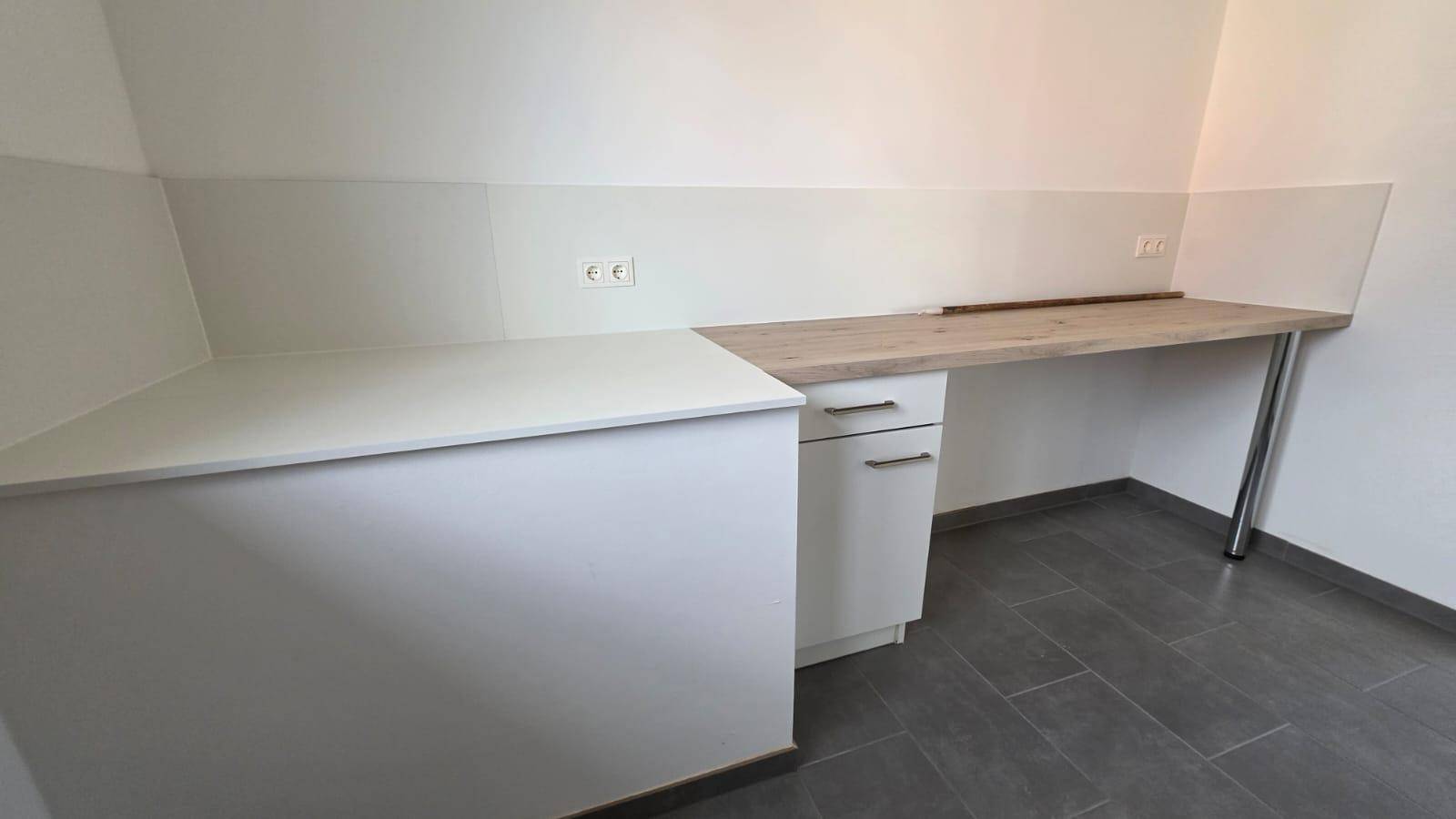 Erweiterter Küchenbereich mit Holzarbeitsplatte und weißen Unterschränken, ideal als Frühstücksbar.