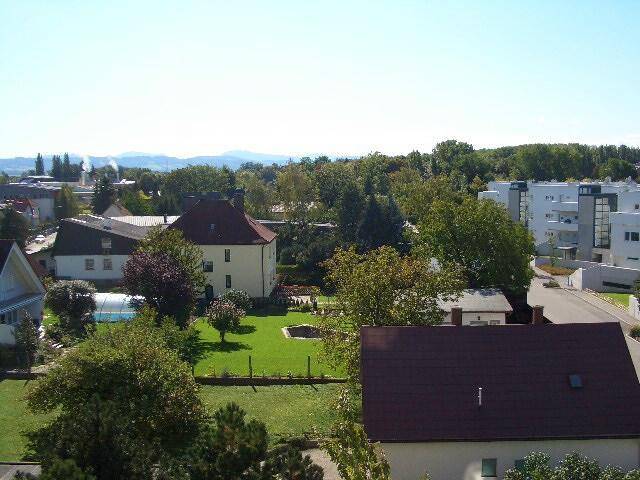 Weitläufiger Blick über eine grüne Wohnsiedlung mit Häusern und Bäumen.