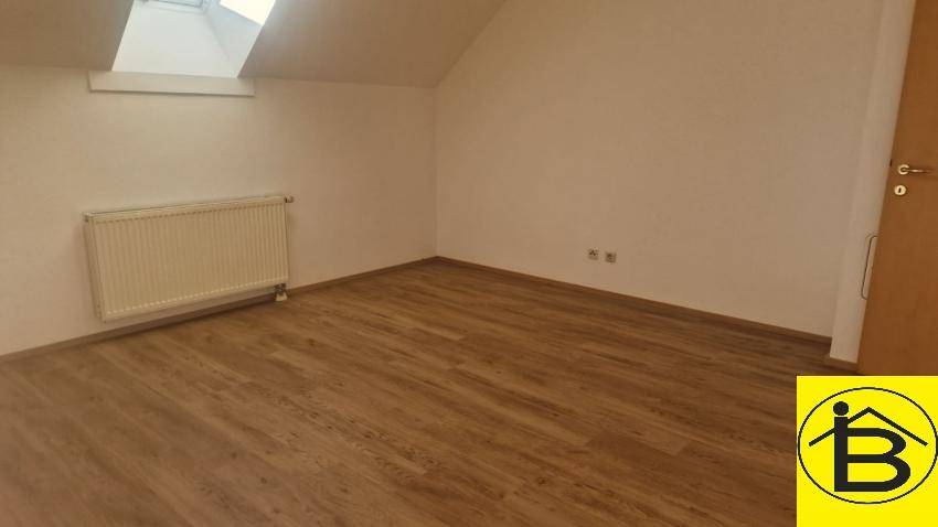 Helles Zimmer mit Holzboden, Dachfenster und Heizkörper, bereit zum Einrichten.