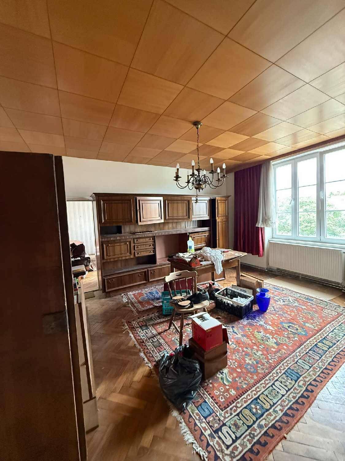 Geräumiges Zimmer mit Holzparkettboden, Holzdecke und älteren Möbeln, bereit zur Renovierung.