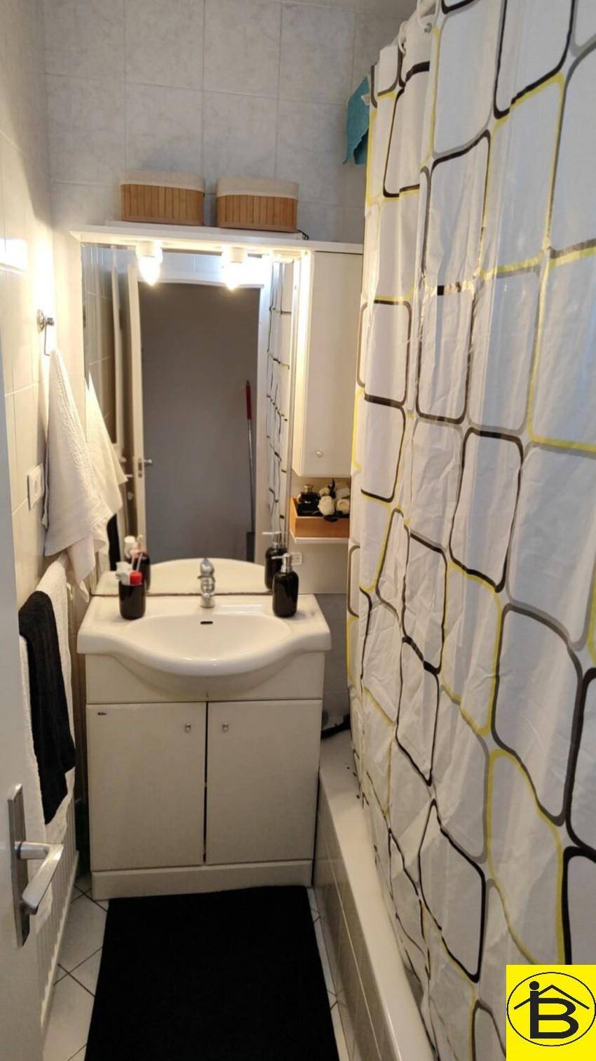 Badezimmer mit Waschbecken, Spiegelschrank und Duschvorhang über der Badewanne.