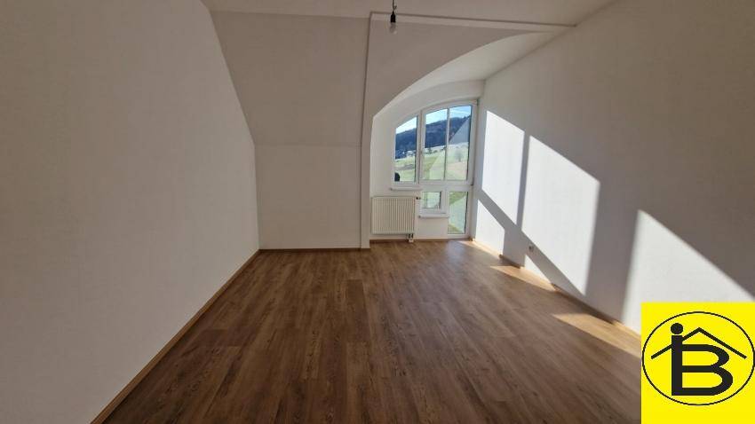 Geräumiges Zimmer mit Holzboden, weiß gestrichenen Wänden und großem Fenster mit Bergblick.