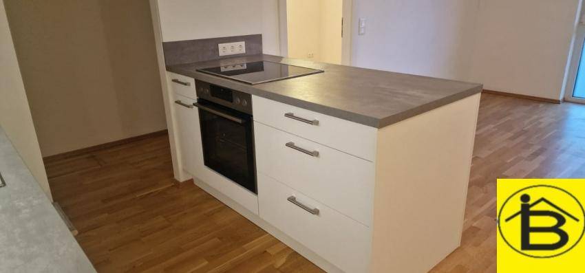 Moderne Kücheninsel mit Kochfeld und Backofen, umgeben von hellem Parkettboden.
