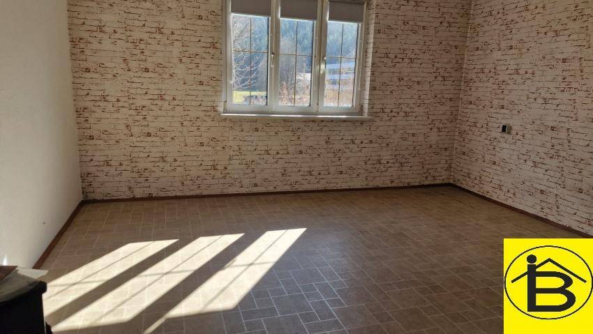 Leerer Raum mit Fliesenboden, Ziegelstein-Tapete und viel natürlichem Licht durch große Fenster.