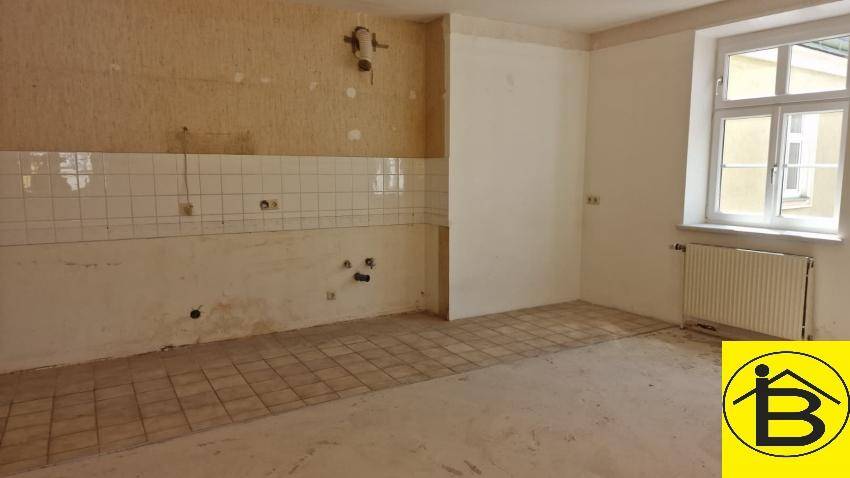 Raum für eine Küche mit Fliesen an der Wand und Anschlüssen, bereit für den Einbau.