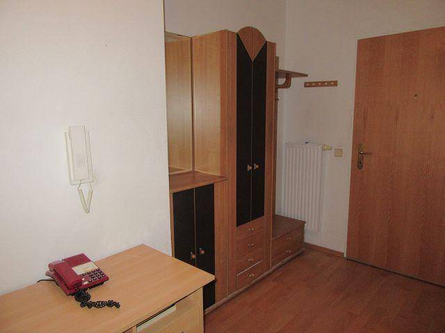 Eingangsbereich mit Garderobenschrank, Telefon und Holzboden, praktisch und einladend gestaltet.