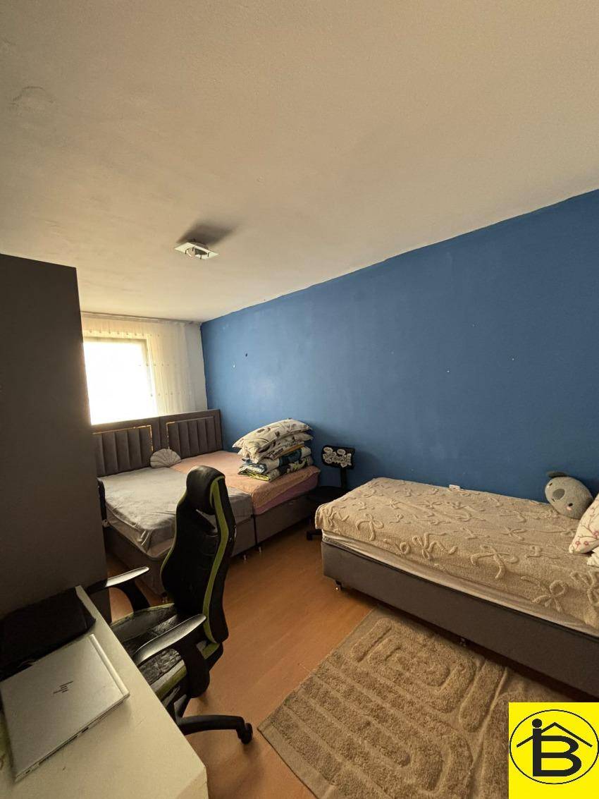 Kinder- oder Gästezimmer mit zwei Betten, Schreibtisch und einer farbigen Akzentwand.