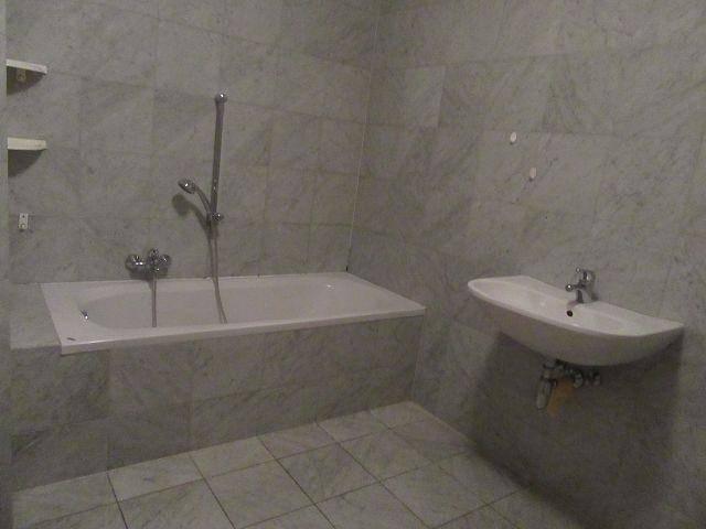 Badezimmer mit Badewanne, Waschbecken und hellen Fliesen an Wänden und Boden, funktional und sauber.