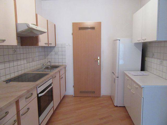Helle Küche mit Einbauschränken, Kühlschrank und ausreichend Arbeitsfläche für den täglichen Gebrauch.