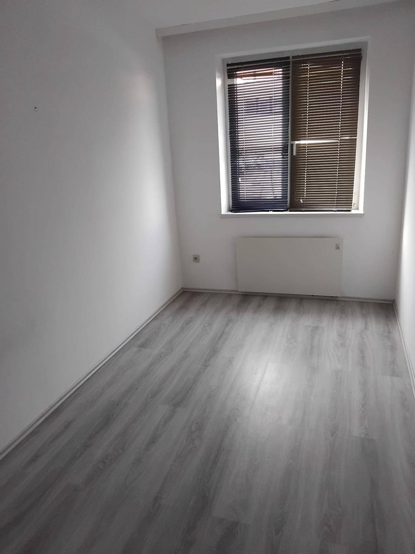 Helles Zimmer mit Fenster und Jalousien, bietet eine ruhige Atmosphäre.