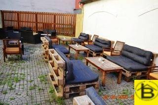 Geräumige Außenterrasse mit Palettenmöbeln und Holztischen, ideal für entspannte Stunden im Freien.
