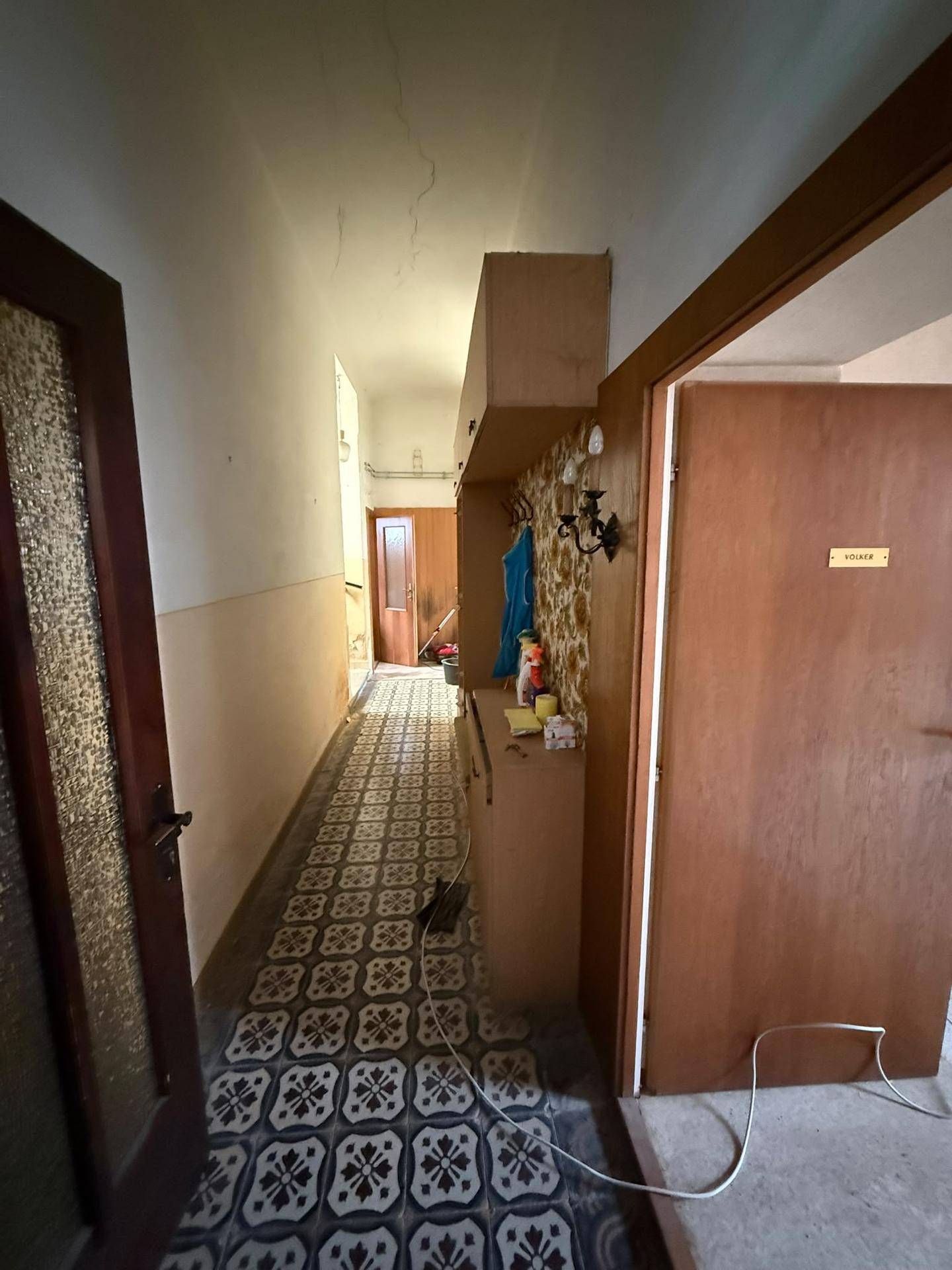 Langer Flur mit gemusterten Bodenfliesen und einer Garderobe.