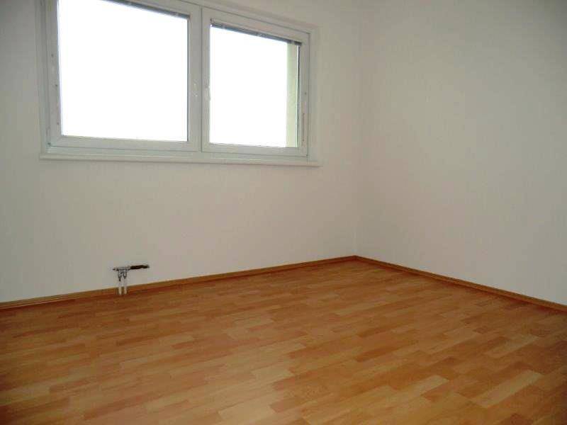 Ruhiges Schlafzimmer mit Laminatboden und einem Fenster, das viel Licht hereinlässt.