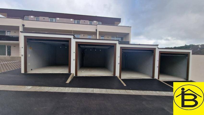 Reihe von Garagen mit Zufahrt vor einem modernen Wohngebäude, ideal für Fahrzeuge.