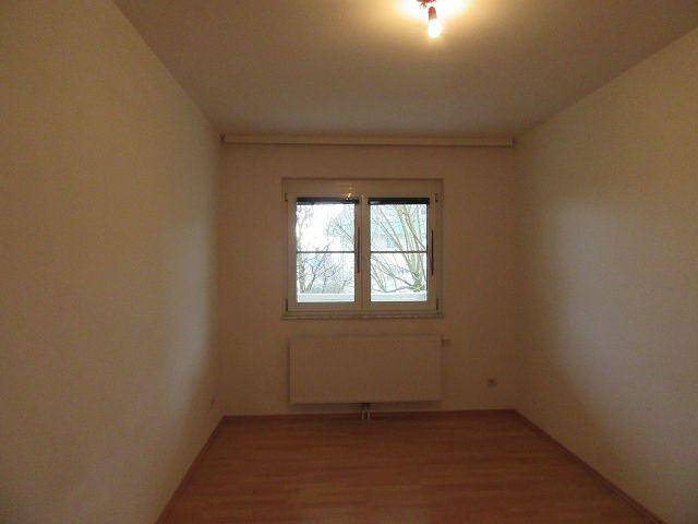 Leeres Zimmer mit Parkettboden und Fenster, ideal als Schlaf- oder Arbeitszimmer, hell und geräumig.