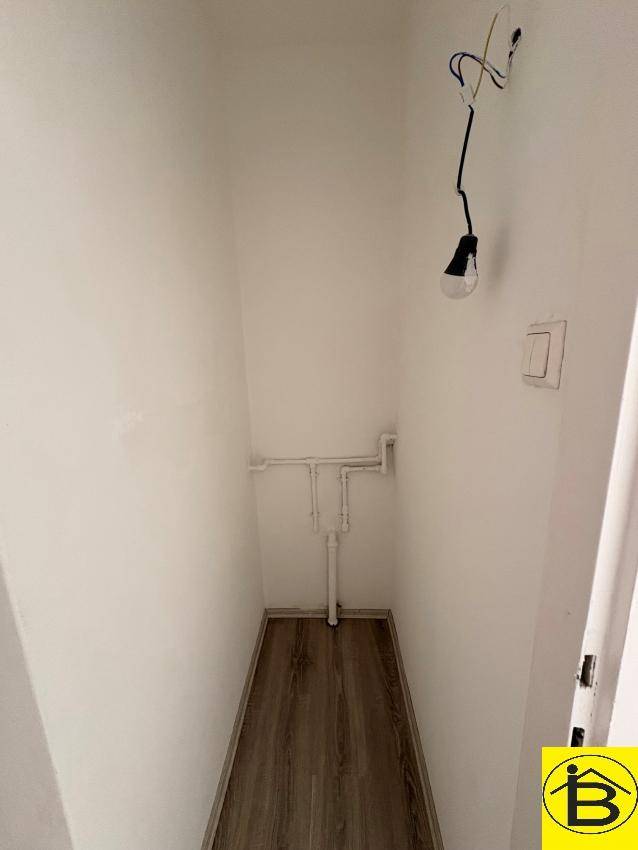 Kleiner Abstellraum mit sichtbaren Rohrleitungen und Laminatboden, ideal für zusätzlichen Stauraum.