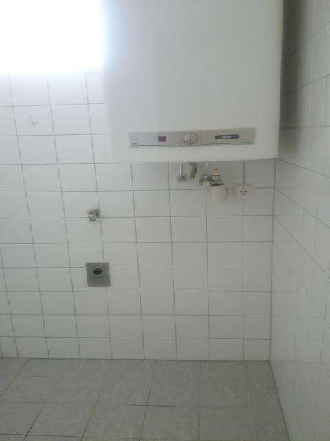 Gefliester Raum mit Wandheizung und Anschlüssen, bereit für die Installation weiterer Elemente.