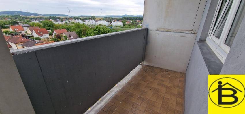 Balkon mit Fliesenboden und weitem Blick über die Dächer und Landschaft.