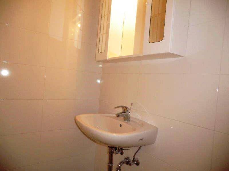 Modernes Badezimmer mit weißen Fliesen, einem Waschbecken und einem Spiegelschrank.