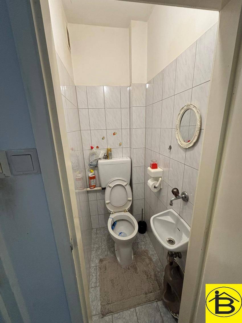Separates WC mit Toilette und kleinem Handwaschbecken, komplett gefliest.
