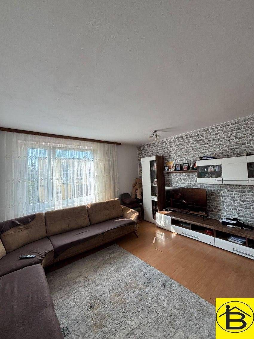 Wohnzimmer mit modernem TV-Möbel, Ecksofa und einer Akzentwand in Ziegelsteinoptik.